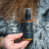 Image d'un après-shampoing pour barbe tenu dans la main d'un homme au style viking. Le packaging robuste et élégant reflète la puissance de ce soin spécialement conçu pour adoucir et nourrir la barbe en profondeur. Idéal pour renforcer et démêler les poils, cet après-shampoing complète parfaitement la routine des barbes épaisses et bien entretenues.